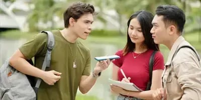 Continuous Communication 3 students on speaking into mobile phone.