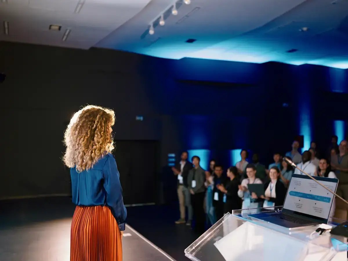 Female speaker presenting in front of an audience.