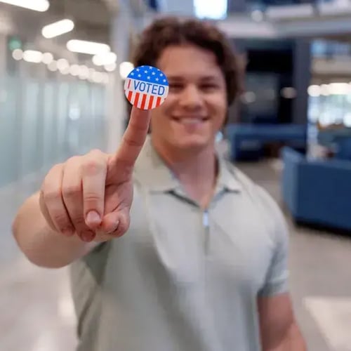 Image of a teenage boy holding a I voted sticker.